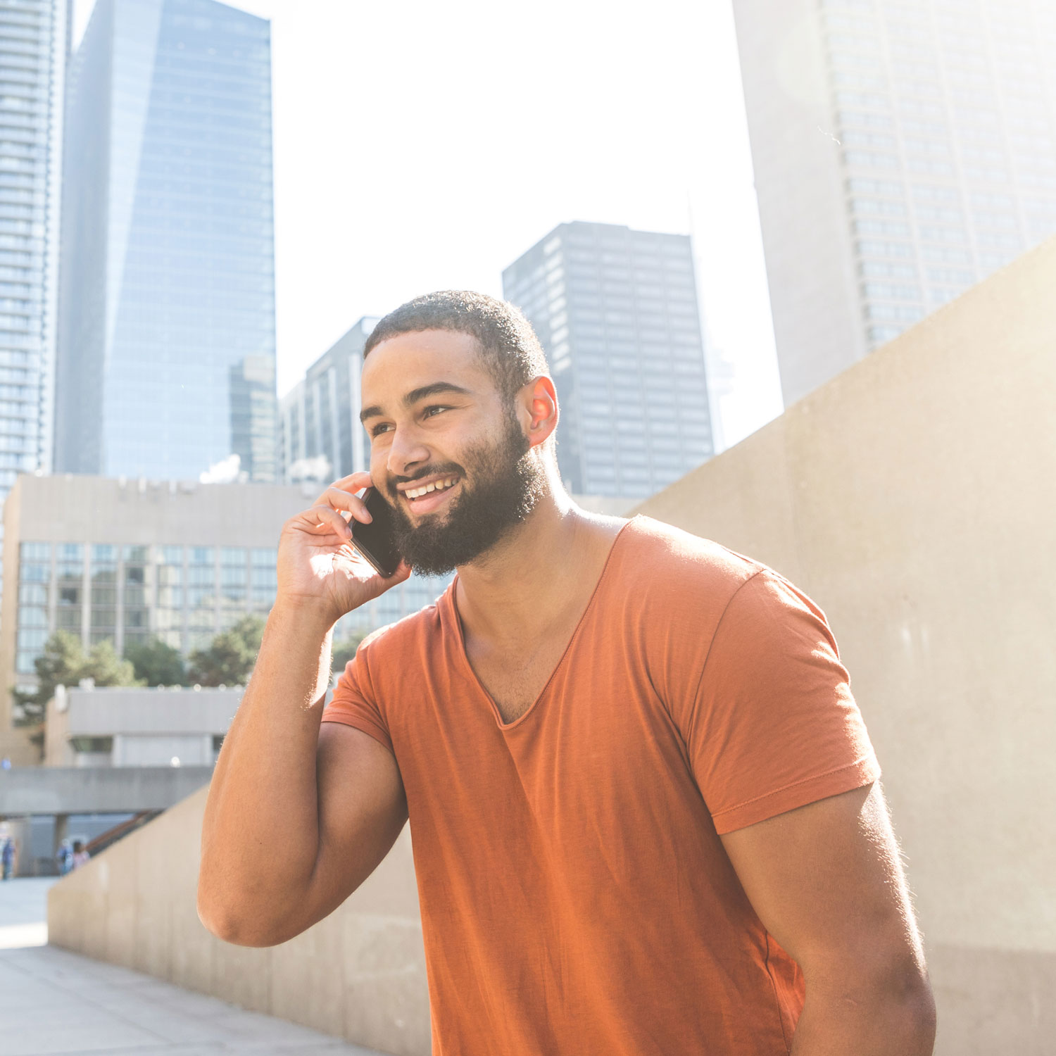 A man in an orange shirt holding a phone.