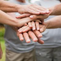 People in a circle stacking hands.